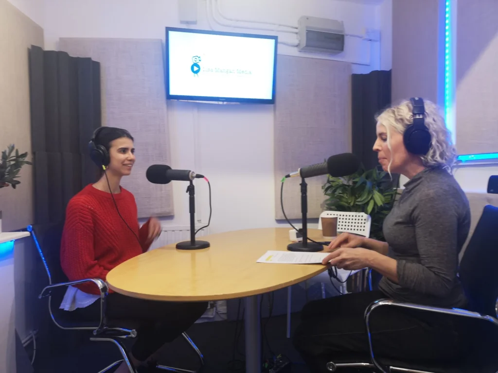 Two women speaking into microphones in a radio interview