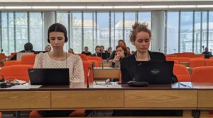Two women sat side by side at laptops in plenary room