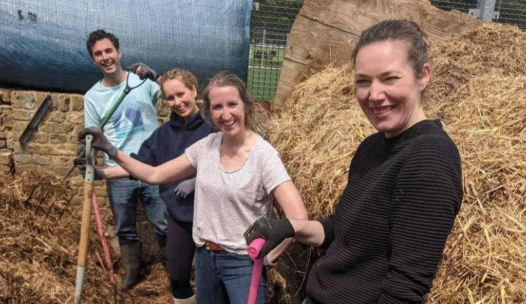 Group of four people stood amongst hay bales.