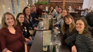 Image of people sitting around a long rectangular table at a restaurant all smiling.