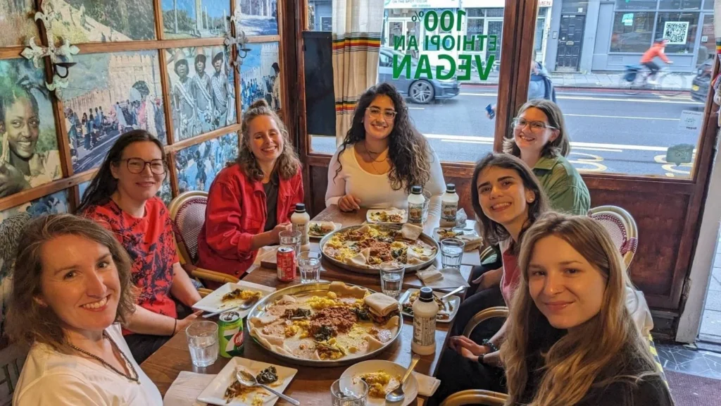Group of women sat around table in restaurant with plates of food to share