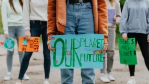 Image of women holding banners at protest at knee height. Banner reads: Our Planet, Our Future.