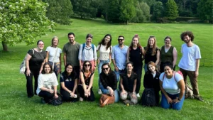 A group of people pose for a photo on grass in two rows.