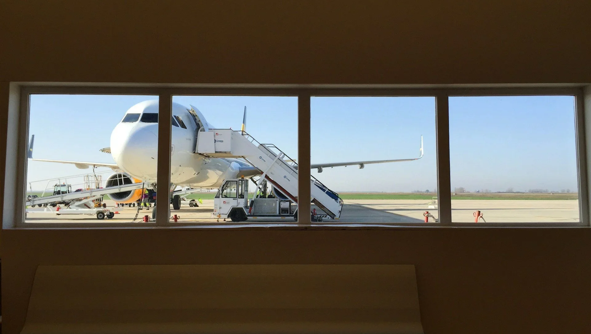 Looking through airport window to see an airplane on the runway
