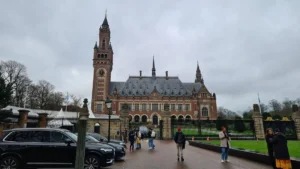 Photo of the International Court of Justice in the Hague, Netherlands. It is a brown building with a tall tower on the left end.