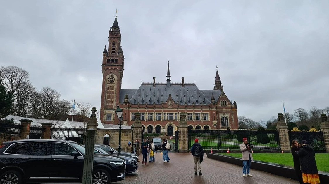 Photo of the International Court of Justice in the Hague, Netherlands. It is a brown building with a tall tower on the left end.