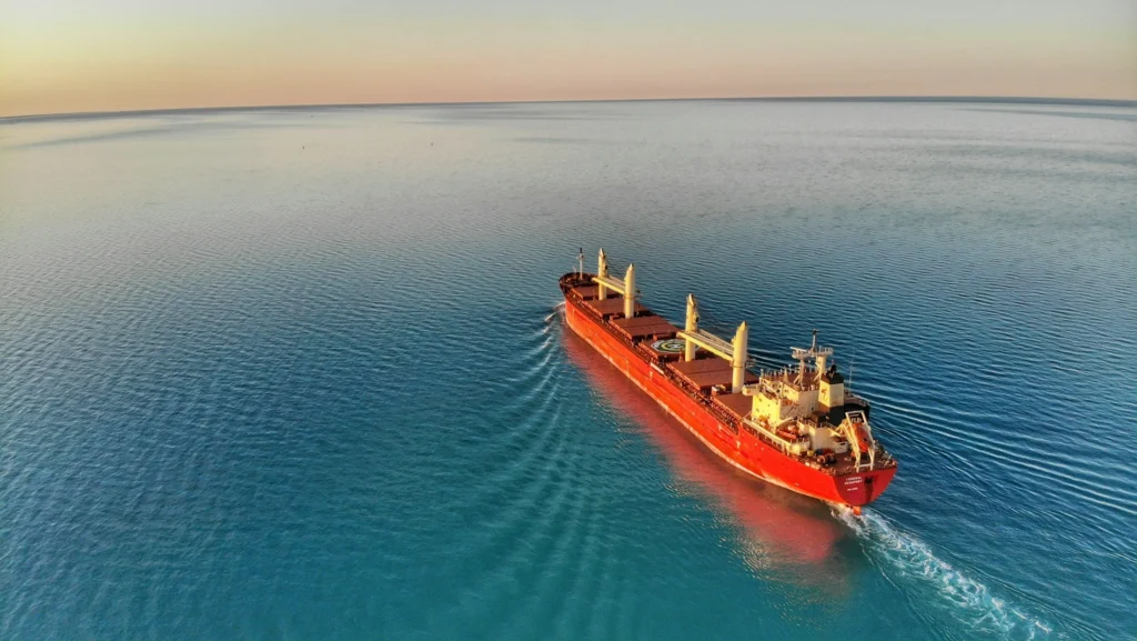 Ship sailing across clear blue ocean towards horizon