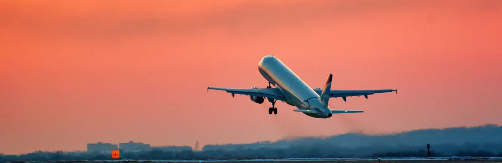 Plane taking off against a red sky