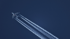 A jet plane with large contrails in its wake across the sky