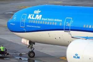 A bright blue KLM jet on the runway of an airport
