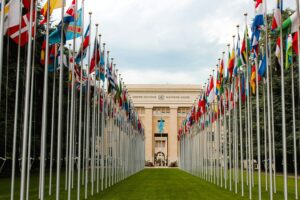 Two large rows of international flags leading to the cream-coloured United Nations building