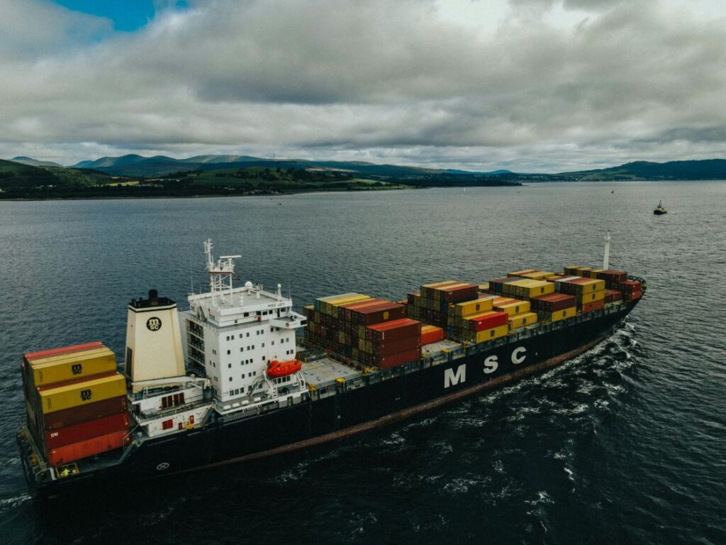 A ship containing cargo containers on a dull, cloudy day