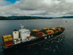 A ship containing cargo containers on a dull, cloudy day