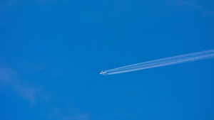 Aeroplane issuing contrails across a deep blue sky