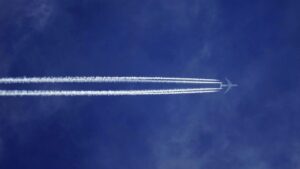 Aeroplane flying high above a deep blue sky leaving two thick white contrails behind it
