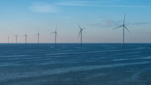 Row of wind turbines in the ocean with a blue and pink sky
