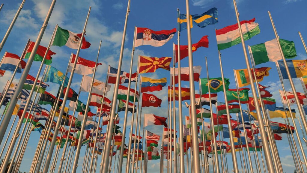 Lots of world flags on poles with a blue sky in the background