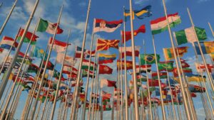 Lots of world flags on poles with a blue sky in the background