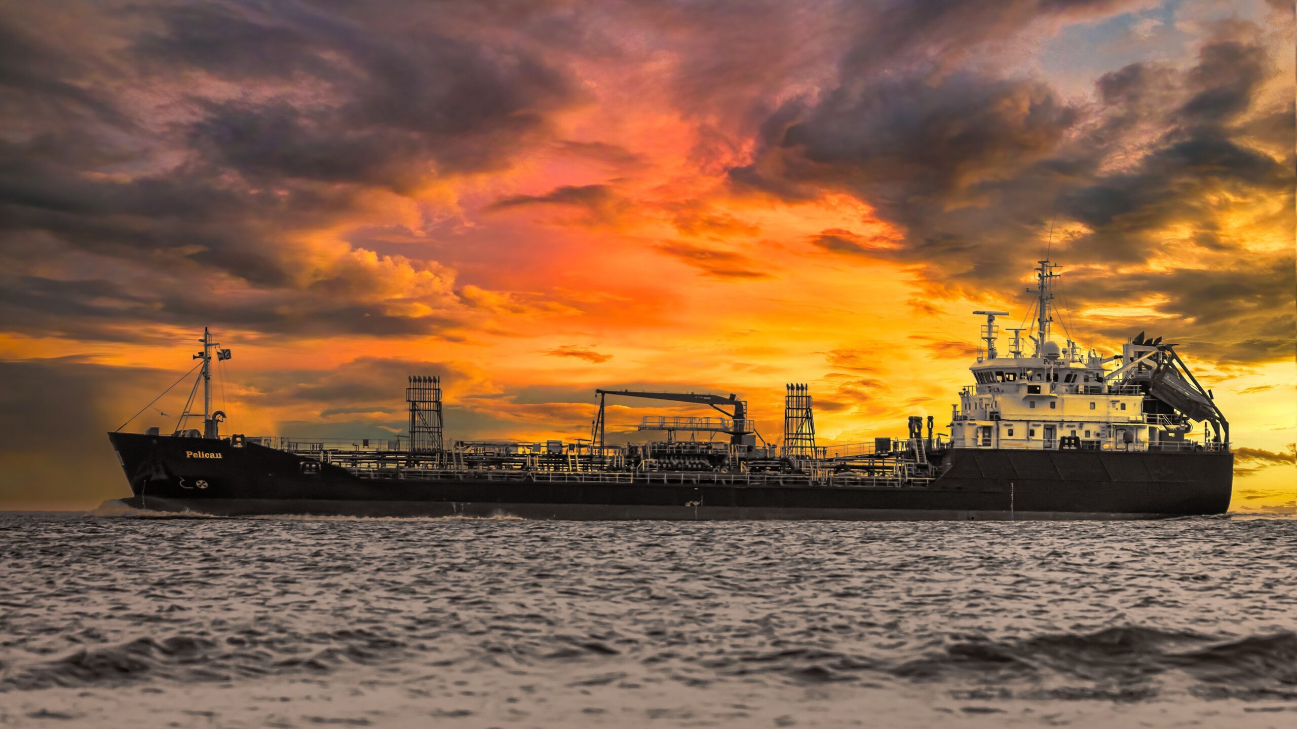 A large cargo ship pictured against a stunning red and orange sunset