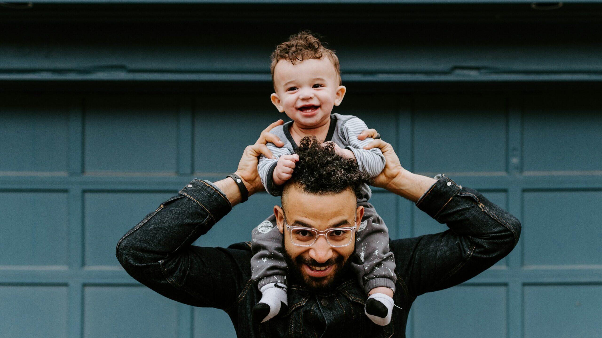 Smiling Dad balancing his happy baby on his shoulders