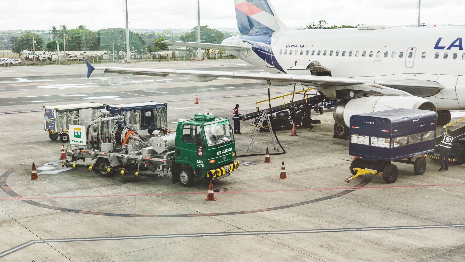 Airplane and airport with fuelling trucks.