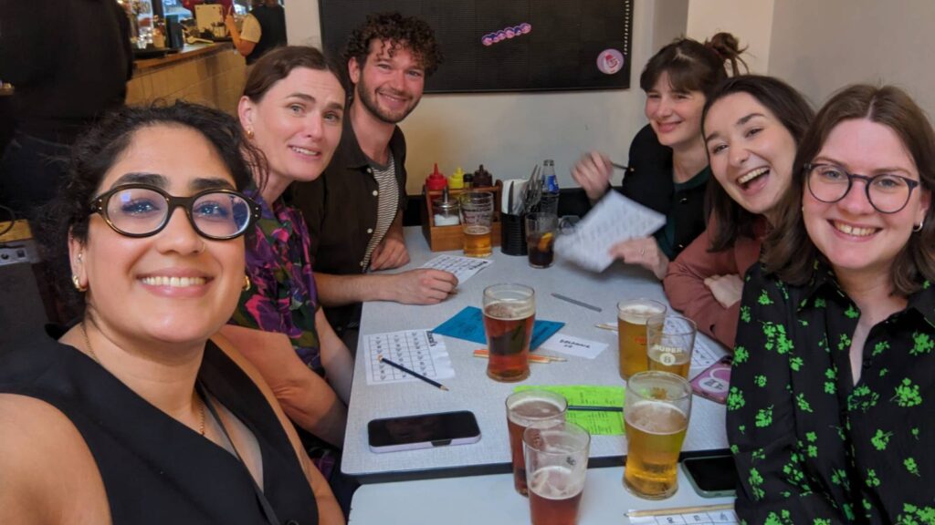 A smiling group shot of work colleagues enjoying a drink and playing bingo