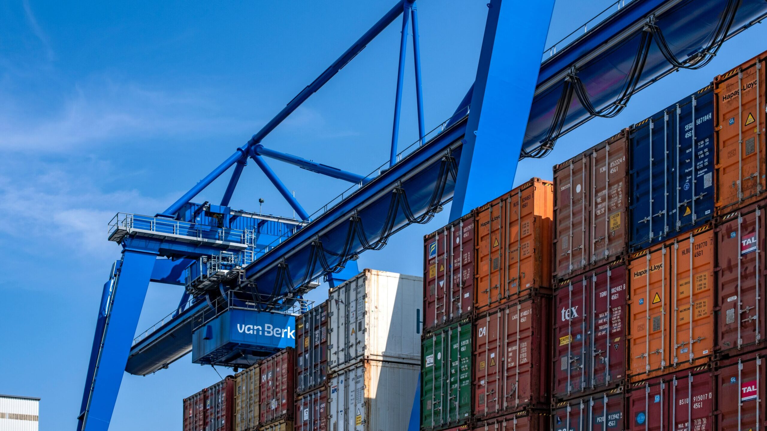 Gantry crane positioned over rows of stacked shipping containers