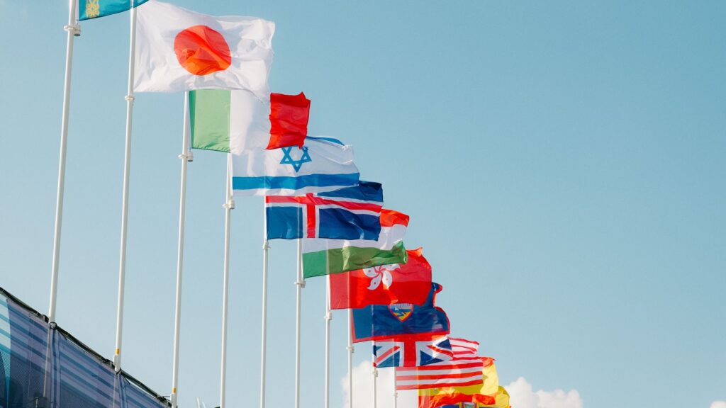 Selection of world flags on flagpoles, with Japanese flag at forefront