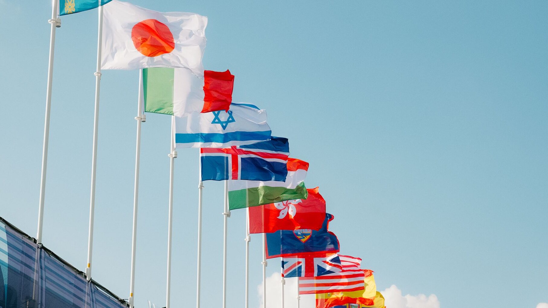 Selection of world flags on flagpoles, with Japanese flag at forefront